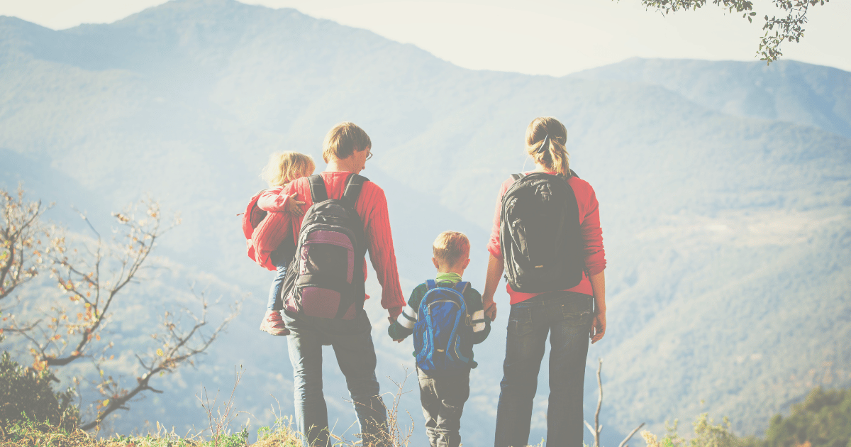 Family with backpacks hiking looking at view on top of mountain